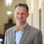 A man in a suit and bow tie smiling for the camera.