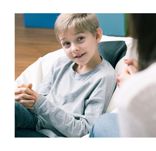 A boy sitting in front of another person.